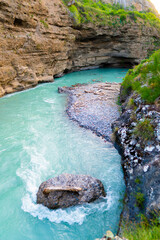 Turquoise mountain river with rapids flowing between cliffs, top view of gorge and rocks.