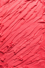 Overhead view of red lipstick, red cream blush and red cosmetic spread on a white background, red cream texture spread on a white countertop