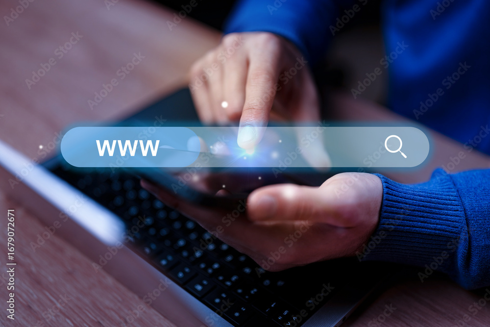 Poster searching for information online using a smartphone during evening hours while seated at a desk