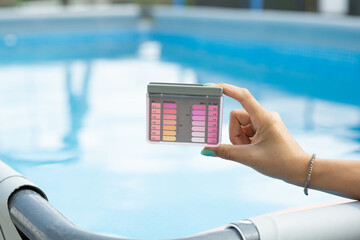 Woman Testing Backyard Swimming Pool Water Quality with a Handheld Tester