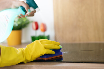 Person wearing yellow gloves cleaning induction cooktop