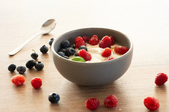 Bowl of yogurt with fresh raspberries, blueberries and honey, healthy breakfast