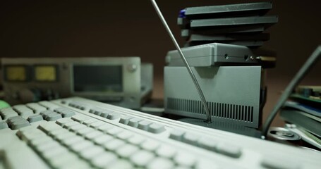 Amidst a cluttered workspace, worn keyboards and retro computer components lie scattered, evoking memories of a bygone digital era filled with innovation and creativity.