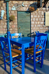 cozy outdoor cafe or restaurant with decorations, located on embankment of Petrovac city, Montenegro, tables and chairs against the background of a stone wall of an old building