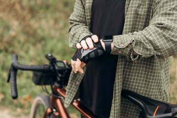 Man cyclist in casual clothes looking at his electronic watch.