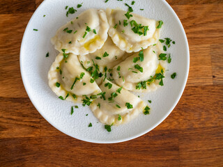 Dumplings - polish pierogies with parsley on wooden table