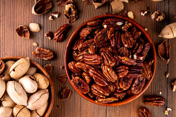 Pecans, peeled and shelled, whole and crushed into pieces. Candied caramelized and raw fresh pecans, autumn harvest, delicious snack, ingredient for baking, pies, cookies