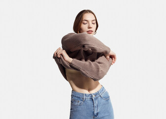 A beautiful woman takes off her beige autumn sweater