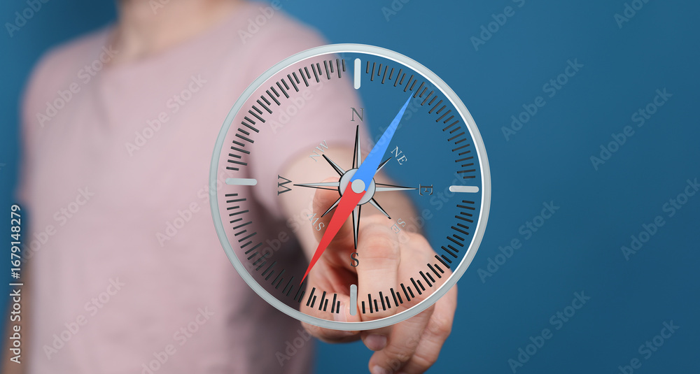 Poster close-up of a hand interacting with a digital compass, showing direction and navigation.