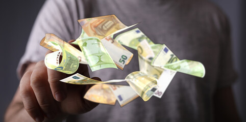 Image of a man's hand with  euro banknotes floating around it.  Perfect for finance, money, and...
