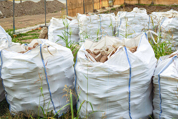 Construction waste recycling: natural stones and bricks in bulk bags for sustainable building materials. Eco-friendly demolition debris management and circular economy practices in green industry