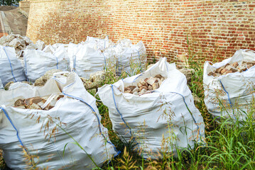 Heavy sacks of masonry fragments staged for pickup. Bricks in bags. Resource efficiency in construction: material recovery, lower emissions, climate-conscious workflows and carbon footprint reduction.