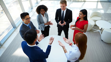 Photo of a diverse group of business professionals in a modern office setting are engaged in a lively discussion around a circular table