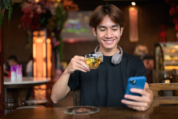 Young Thai Asian man using phone inside cafe restaurant