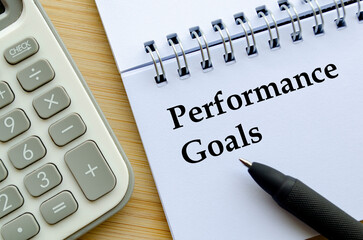 A professional notepad with calculator and pen showing performance goals concept