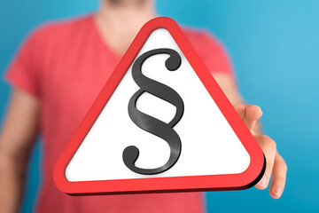 Stock photo of a hand presenting a warning sign with a paragraph symbol, symbolizing legal matters.
