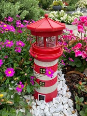 Roter Leuchtturm kreativ integriert in die Natur mit Blumen