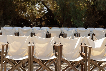 Rows of empty canvas director chairs in an outdoor setting. Perfect for summer movie night, event, or theater concepts.