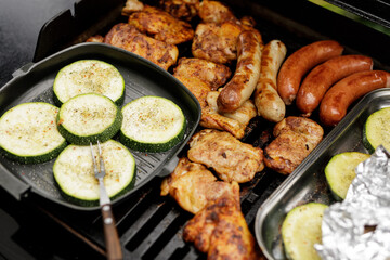 Delicious summer BBQ feast! Grilled chicken, sausages, and zucchini.