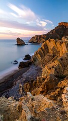 Dramatic coastal scenery at sunrise, showcasing a rugged coastline with soft, flowing clouds and a calm, tranquil ocean.