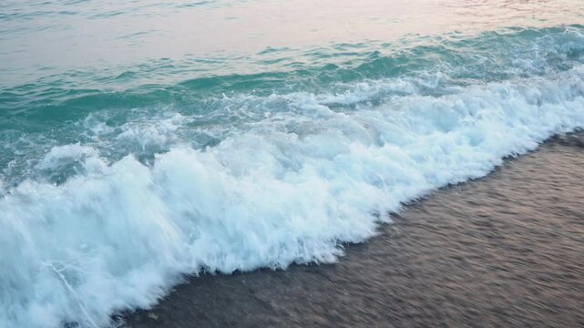 Gentle waves lap against the sandy shore as the sun rises over the Adriatic Sea in Canj, Montenegro. The serene atmosphere invites relaxation and reflection in the golden morning light
