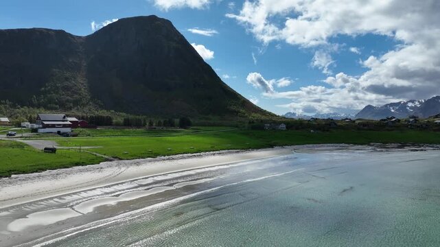 Reverse aerial over Hov Beach on Gimsoy island, Lofoten, with Hoven Mountain backdrop, idyllic summer scenery.