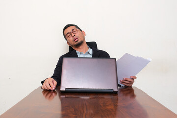 An office employee sleeping at his working desk