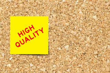 Yellow note paper with word high quality on cork board background with copy space