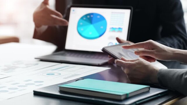 ノートパソコンとタブレットPCの画面を見ながら会議するビジネスパーソンのグループ