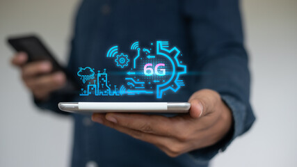 Man holding smartphone with 6G hologram showing smart city, wireless signal, and gear icon. Concept of mobile technology, high-speed internet, IoT, innovation, and next-generation network.