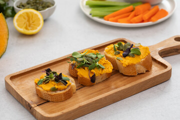 Healthy autumn snack with pumpkin spread and seed topping on wooden board. Pumpkin hummus