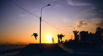 Backlight Silhouette of skater on skateboard jumping sunset sky at skate park, Skateboarding on...