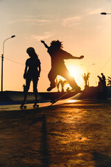 Backlight Silhouette of skater on skateboard jumping sunset sky at skate park, Skateboarding on...