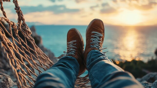 A person's feet hanging from a hammock, overlooking a serene ocean at sunset, with a warm, golden hue illuminating the scene. - Powered by Adobe