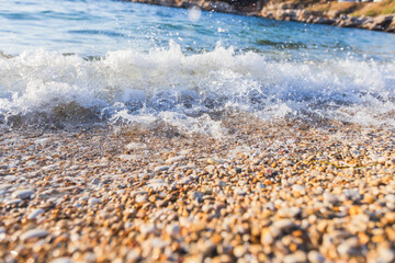 Soothing waves gently lapping against smooth pebble shore with sparkling foam and crystal clear water creating peaceful natural beach atmosphere.