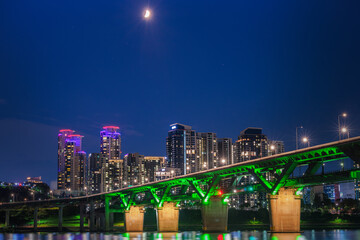The splendid night view of Cheongdam Bridge on the Han River in Seoul, South Korea, with the first quarter moon in the night sky