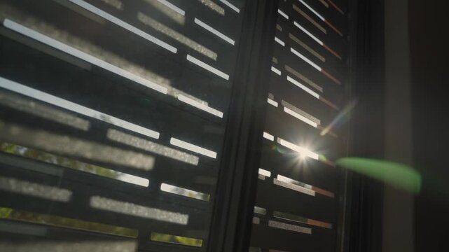 Modern metal window shutters letting the sun's rays and lens flare pass through the openings in contemporary architectural setting. Hope and peace in early morning. Green energy solutions