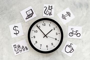 Wall clock and many paper cards with hand drawing of different life activities, top view. Time...