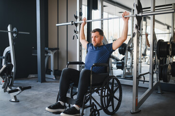 Man with disability lifting weights in wheelchair at gym for rehabilitation