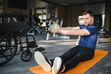 Wheelchair user training with medicine ball in gym for rehabilitation