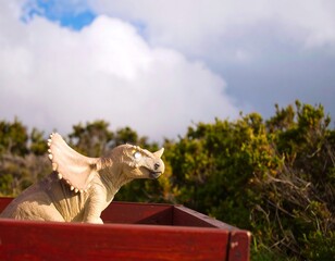 Dinosaur figurine in a wooden crate outdoors