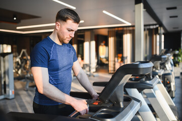 Fototapeta premium Determined athlete using treadmill for rehabilitation in modern gym
