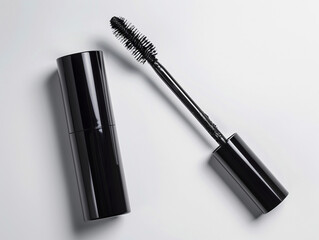 Obraz premium Elegant black mascara positioned alongside its tube against a clean backdrop highlights the beauty of makeup artistry