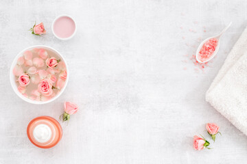 Roses essence water in bowl with petals and skin care cosmetic products with flowers essential oil