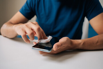 Close-up of male hands carefully cleaning smartphone screen with wet wipe and alcohol pad, wiping away dirt and fingerprints for optimal device hygiene. Concept of healthy lifestyle.