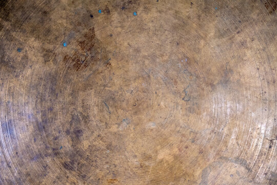 Close-up of an aged, textured brass surface with circular patterns.
