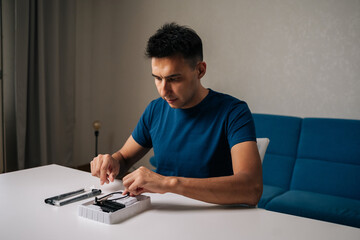 Focused technician male assembling wi-fi module using tools at home office desk, focusing on...