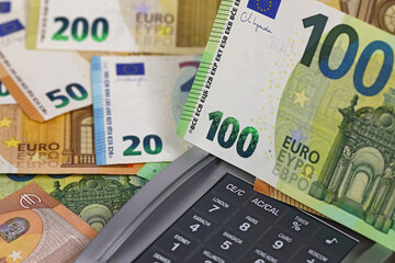 A partially visible calculator is covered with European Union banknotes