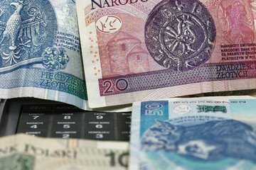 Among the banknotes of the Polish zloty, the keyboard of a calculator can be partially visible
