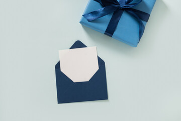 Blue gift box, envelope and empty blank on pastel blue background. Flat lay. View from above. Copy space. Happy Fathers Day